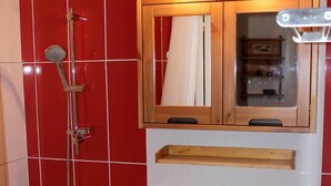 Ein Badezimmer mit Badewanne, Waschbecken und einem hölzernen Medikamentenschrank.