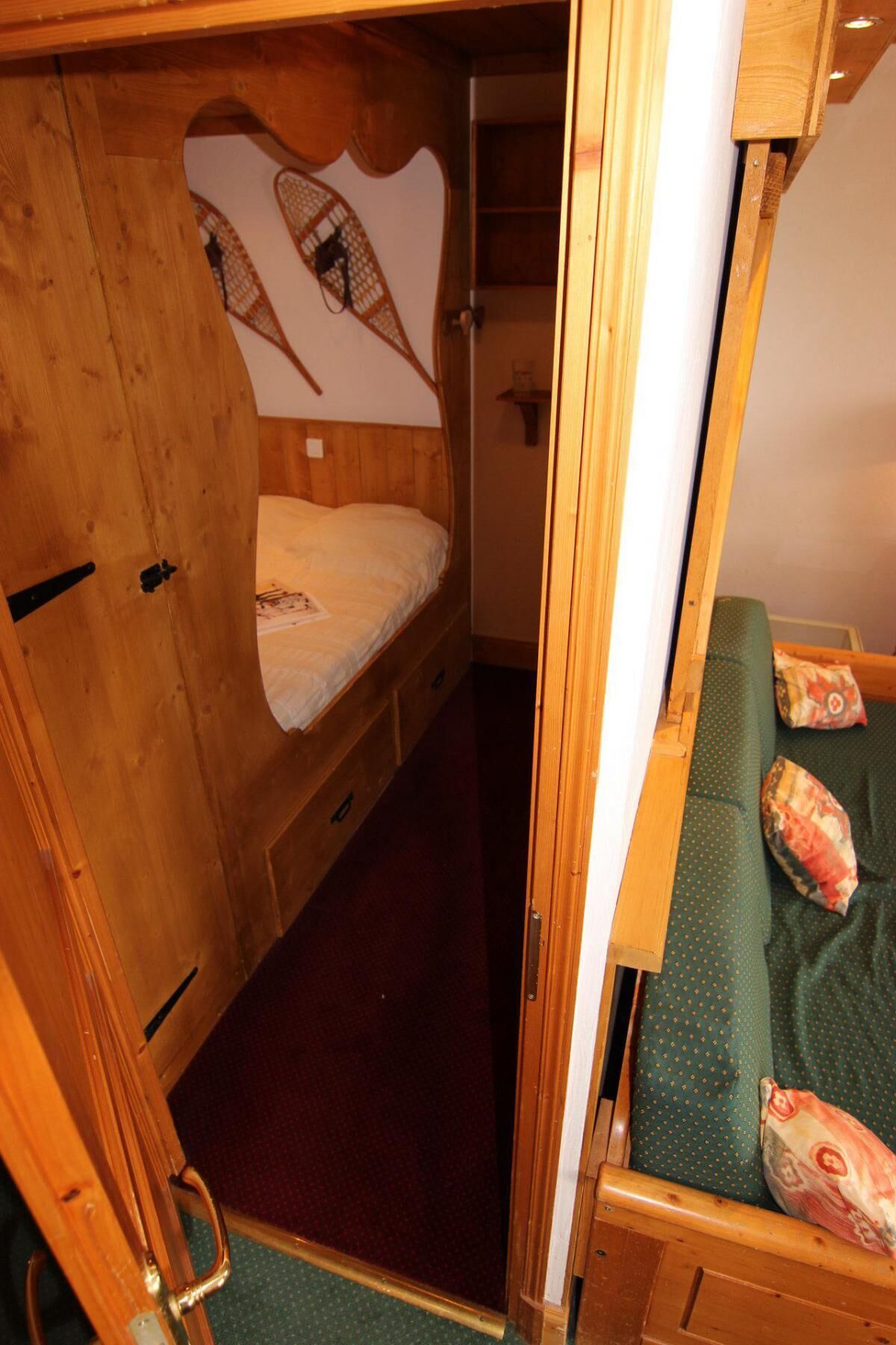 A compact, wooden interior with a bunk bed and a single bed, featuring a simple, functional design.