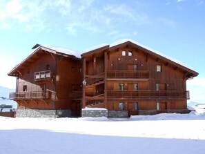 A wooden chalet with multiple balconies and a stone foundation, surrounded by snow. - 100m from resort center, balcony, tv, 50m², Val Thorens (Val Thorens)
