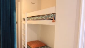 Uma cama beliche com colchão estampado e almofada laranja.