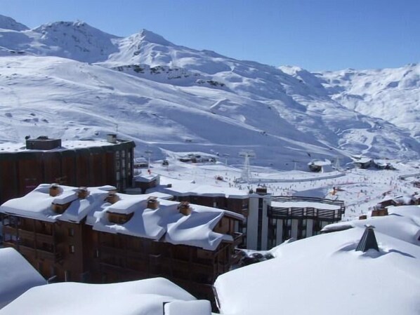 Un pueblo cubierto de nieve en la montaña, con edificios y una pista de esquí.