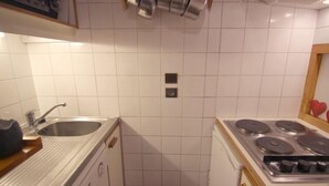 A kitchen with a sink, stove, and cabinets.