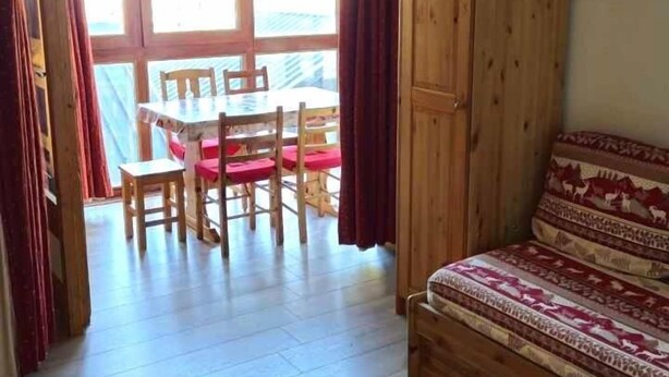 A wooden table and sofa in a room with a wooden floor, a wooden cabinet, and a view through a glass door to an outdoor area with a table and chairs. - 10m from resort center, 2nd floor, tv, 30m², Val Thorens (Val Thorens)