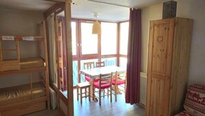 A room with bunk beds, a dining table with chairs, and a wooden cabinet. - 10m from resort center, 2nd floor, tv, 30m², Val Thorens (Val Thorens)
