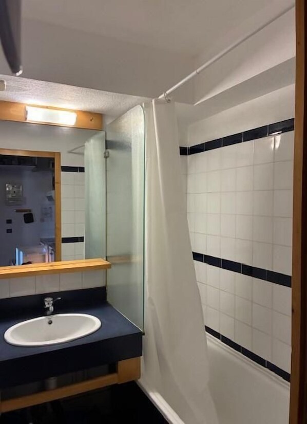 A bathroom with a white sink, a mirror, and a shower curtain.