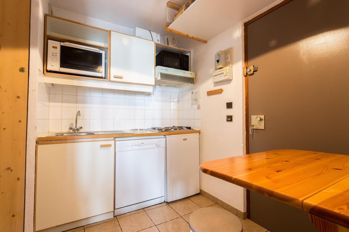 A compact kitchen with a dishwasher, microwave, and stove.