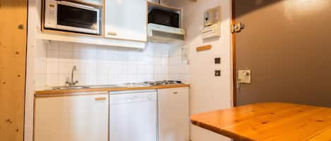 A compact kitchen with a dishwasher, microwave, and stove.