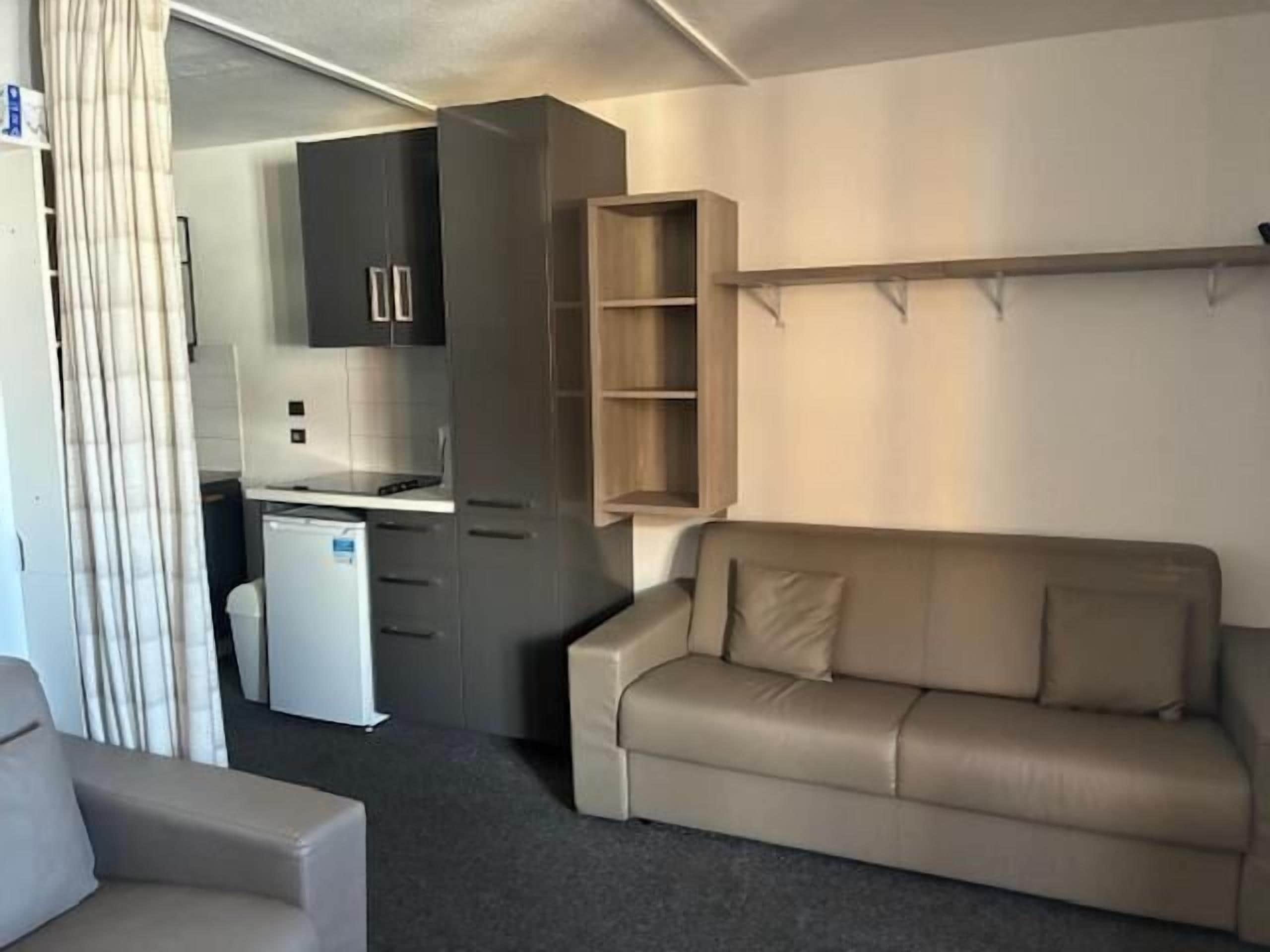 A compact living space with a kitchenette, a sofa, and a small table.