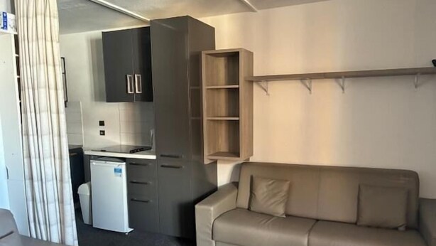 Un espace de vie compact comprenant un coin cuisine, un canapé et une petite table.