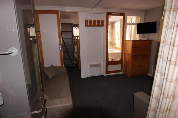 A compact room with a sofa, a wooden dresser, a television, and a door leading to another room. - 50m from ski slopes, 4th floor, balcony, tv, 30m², Val Thorens (Val Thorens)