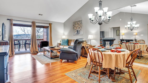A spacious living room with a dining area, large windows, and a fireplace. - Give Your Family a New "Pointe of View" at this 2 bed condo at Pointe Royale! (Branson)