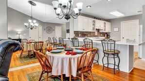 A dining area with a round table, chairs, and a chandelier. There is a kitchen area with cabinets and a countertop. - Give Your Family a New "Pointe of View" at this 2 bed condo at Pointe Royale! (Branson)