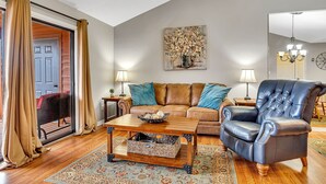 A living room with a brown leather sofa, a black leather armchair, a wooden coffee table, and a patterned rug. - Give Your Family a New "Pointe of View" at this 2 bed condo at Pointe Royale! (Branson)