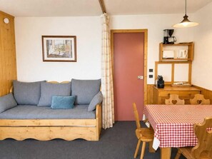 A cozy room with a wooden sofa, a dining table with a checkered tablecloth, and a kitchenette area. - 50m from ski slopes, 5th floor, tv, 35m², Val Thorens (Val Thorens)