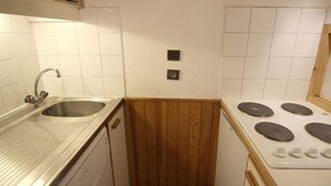 A compact kitchen with a stainless steel sink, wooden cabinets, and a white stove. - 50m from ski slopes, 5th floor, tv, 35m², Val Thorens (Val Thorens)