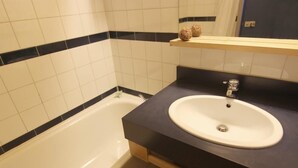 Ein Badezimmer mit einer weißen Badewanne, einem weißen Waschbecken und einer dunklen Arbeitsplatte.