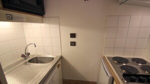 Eine kleine Küche mit Spüle aus Edelstahl, einem Herd und einer Mikrowelle.
