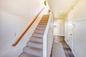 Una escalera con peldaños alfombrados y barandilla de madera, que lleva a una puerta en la parte superior.