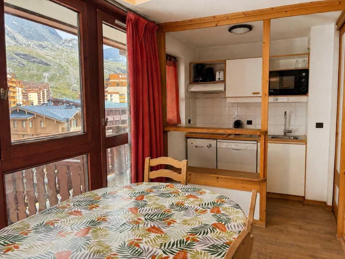 Une pièce comprenant une table à manger, une chaise, un coin cuisine avec un four à micro-ondes et une vue sur les montagnes par la fenêtre.