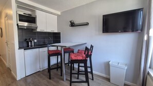 A compact kitchen with a dining area, a TV mounted on the wall, and a trash bin. - 100m from ski slopes, balcony, tv, 23m², Val Thorens (Val Thorens)