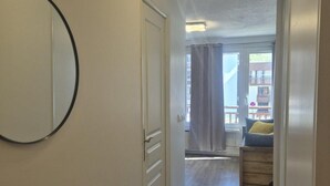 A hallway with a door, a mirror, and a view into a balcony area. - 100m from ski slopes, balcony, tv, 23m², Val Thorens (Val Thorens)