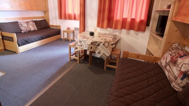 Une petite pièce comprenant un lit, une petite table recouverte d’une nappe et un canapé.