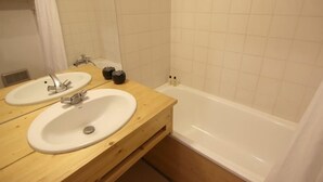 Une salle de bain avec deux lavabos, une baignoire et un meuble-lavabo en bois.