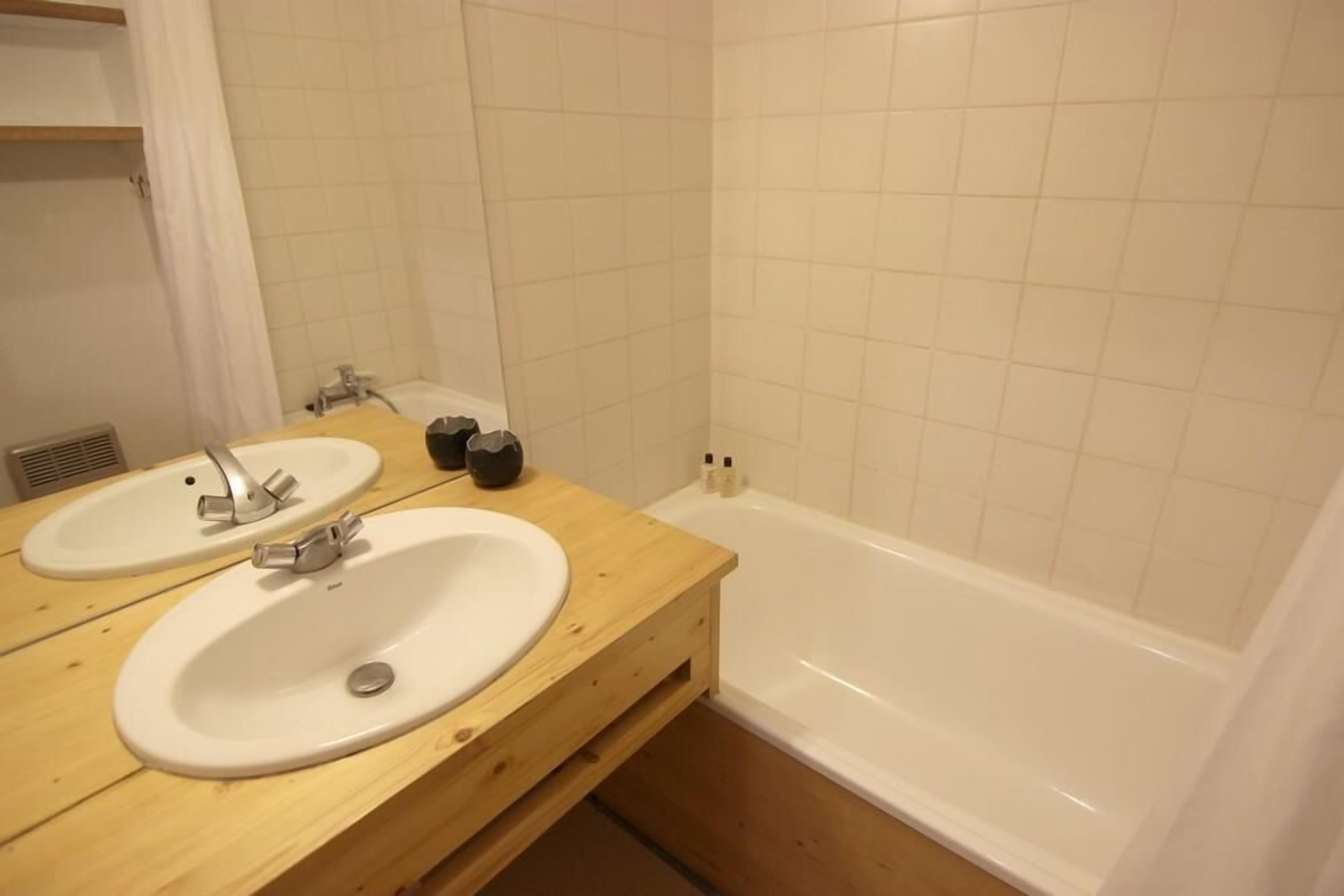 A bathroom with two sinks, a bathtub, and a wooden vanity. - 150m from resort center, 3rd floor, balcony, tv, 24m², Val Thorens (Val Thorens)