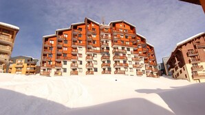 Un hôtel à plusieurs étages doté de balcons, situé dans un environnement enneigé.