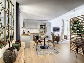 Een moderne keuken met grijze kastjes, een eethoek met rieten stoelen en een groot raam.