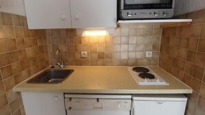 Una cocina compacta con pileta, estufa y lavavajillas.