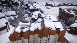 Een hotel met meerdere verdiepingen en een met sneeuw bedekte dak, gelegen in een skigebied.