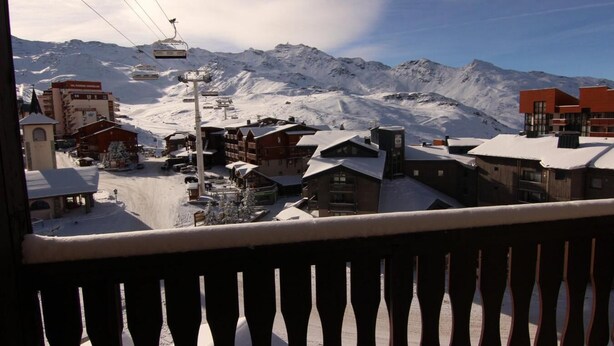 Een bergstad bedekt met sneeuw, met gebouwen, een skilift en een heldere lucht.