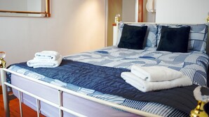 A neatly made bed with a blue and white patterned bedspread, two black pillows, and folded white towels on the side. - Characterful Semi-Detached House; Enviably Located (St Andrews)