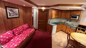 Ein kompakter Wohnbereich mit Sofa, Küchenzeile und Essplatz.