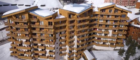 A multi-story hotel with balconies, located in a snowy mountainous area.
