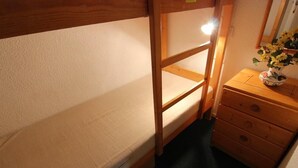 Ein Etagenbett mit Holzrahmen und eine kleine Kommode mit Schubladen.