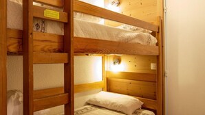 Une chambre avec un lit superposé, des murs en bois et un lit simple en bas.