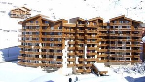 Un hotel de varios pisos con balcones de madera, con una imponente montaña nevada de fondo.