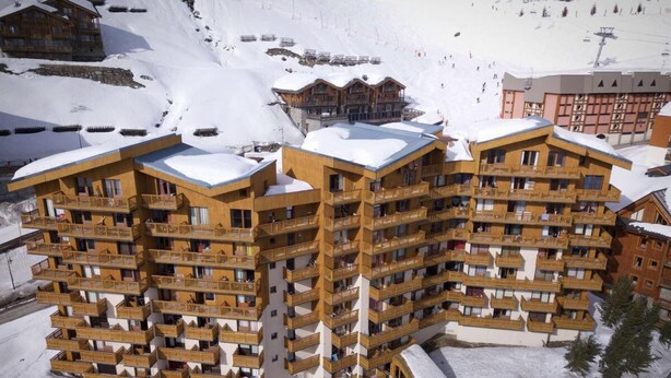 Un hotel de varios pisos con balcones, situado en una zona montañosa nevada.