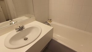Ein Badezimmer mit einem weißen Waschbecken, einem Spiegel und einer Badewanne.