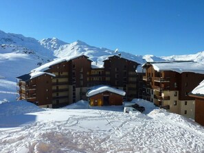 A multi-story hotel with a central entrance and balconies, surrounded by snow-covered mountains. - 150m from ski slopes, 1st floor, balcony, 30m², Val Thorens (Val Thorens)