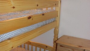 Ein Stockbett mit karierter Bettdecke und eine Holzkommode mit mehreren Schubladen.
