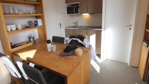 Une cuisine compacte dotée de meubles en bois, d’un four à micro-ondes et d’un coin repas avec une table et des chaises.