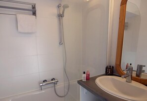 Bathroom features a shower area, glass-enclosed tub, and a sink with a mirror and toiletries.
