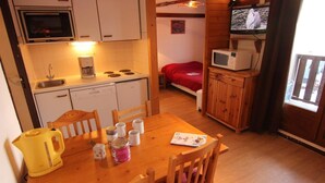 A compact kitchen with a microwave, stove, and sink. There's a dining table with chairs and a television in the corner. - 150m from ski slopes, floor -1, balcony, 29m², Val Thorens (Val Thorens)