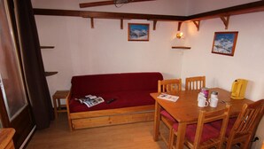 A cozy room with a wooden sofa, a dining table with chairs, and a small wooden cabinet. - 150m from ski slopes, floor -1, balcony, 29m², Val Thorens (Val Thorens)
