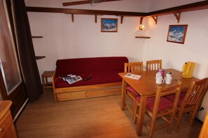 A cozy room with a wooden sofa, a dining table with chairs, and a small wooden cabinet. - 150m from ski slopes, floor -1, balcony, 29m², Val Thorens (Val Thorens)