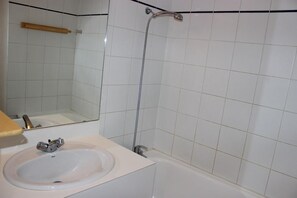 A bathroom with a white sink, a mirror, and a shower.