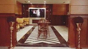 Ein geräumiger Wohnbereich mit großem Fernseher, Holzmöbeln und einem gemusterten Teppich.